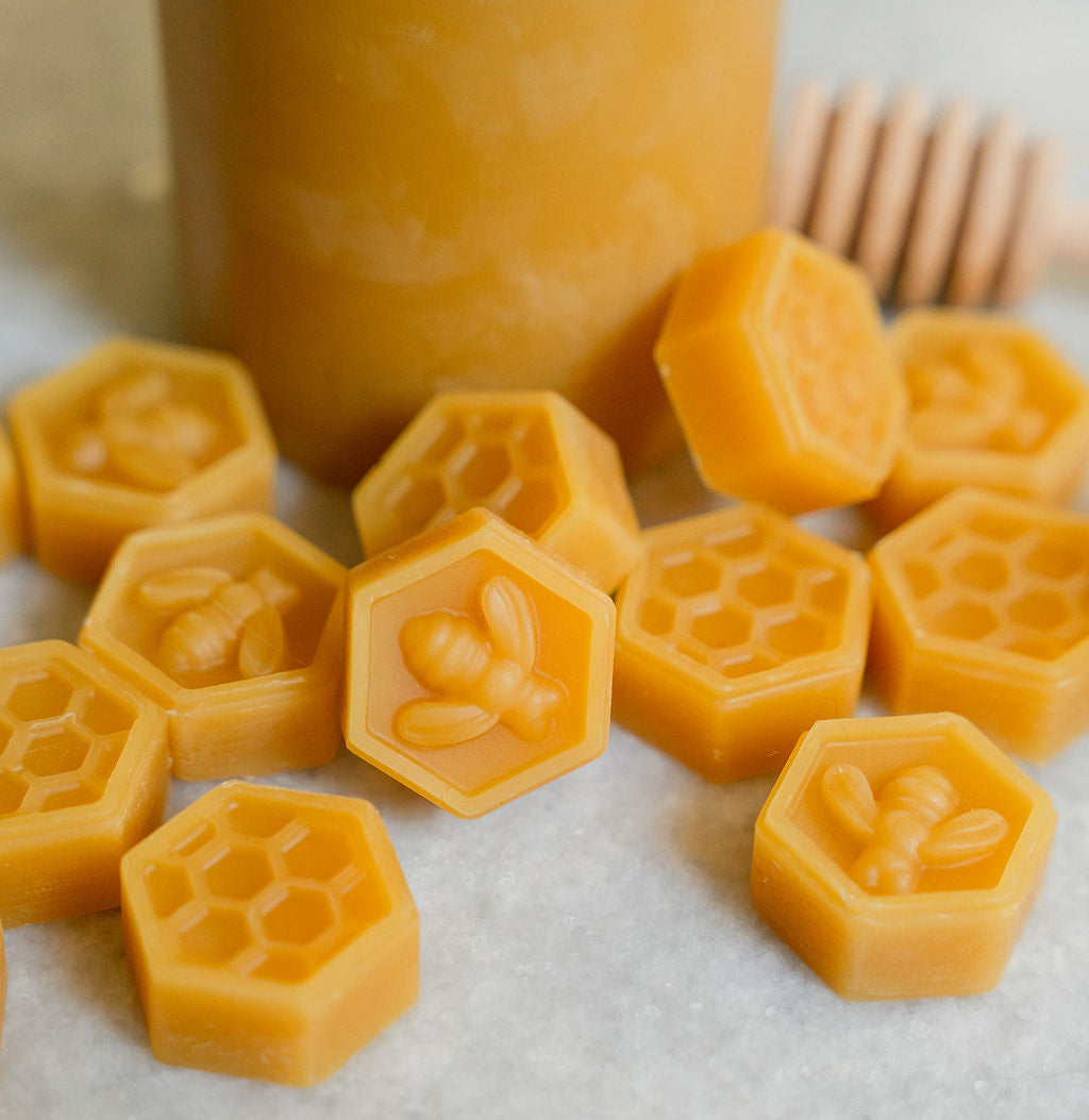 honeycomb-shaped beeswax pieces with a wooden spoon on a light background